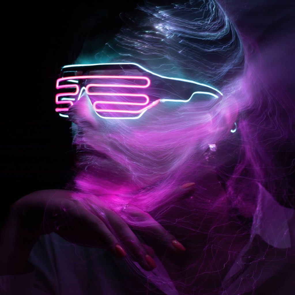 Person mit leuchtender Neonbrille in Blau und Pink, umgeben von dynamischen, strömenden Lichtlinien in dunkler Umgebung.
