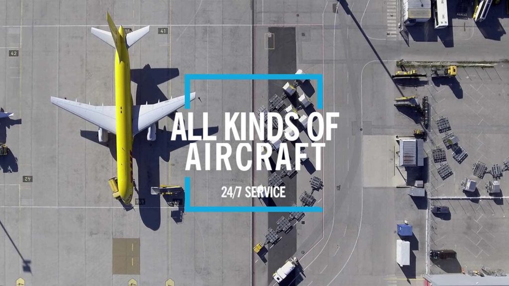 Luftaufnahme eines gelben Frachtflugzeugs auf dem Rollfeld mit Text "ALL KINDS OF AIRCRAFT – 24/7 SERVICE" im Zentrum
